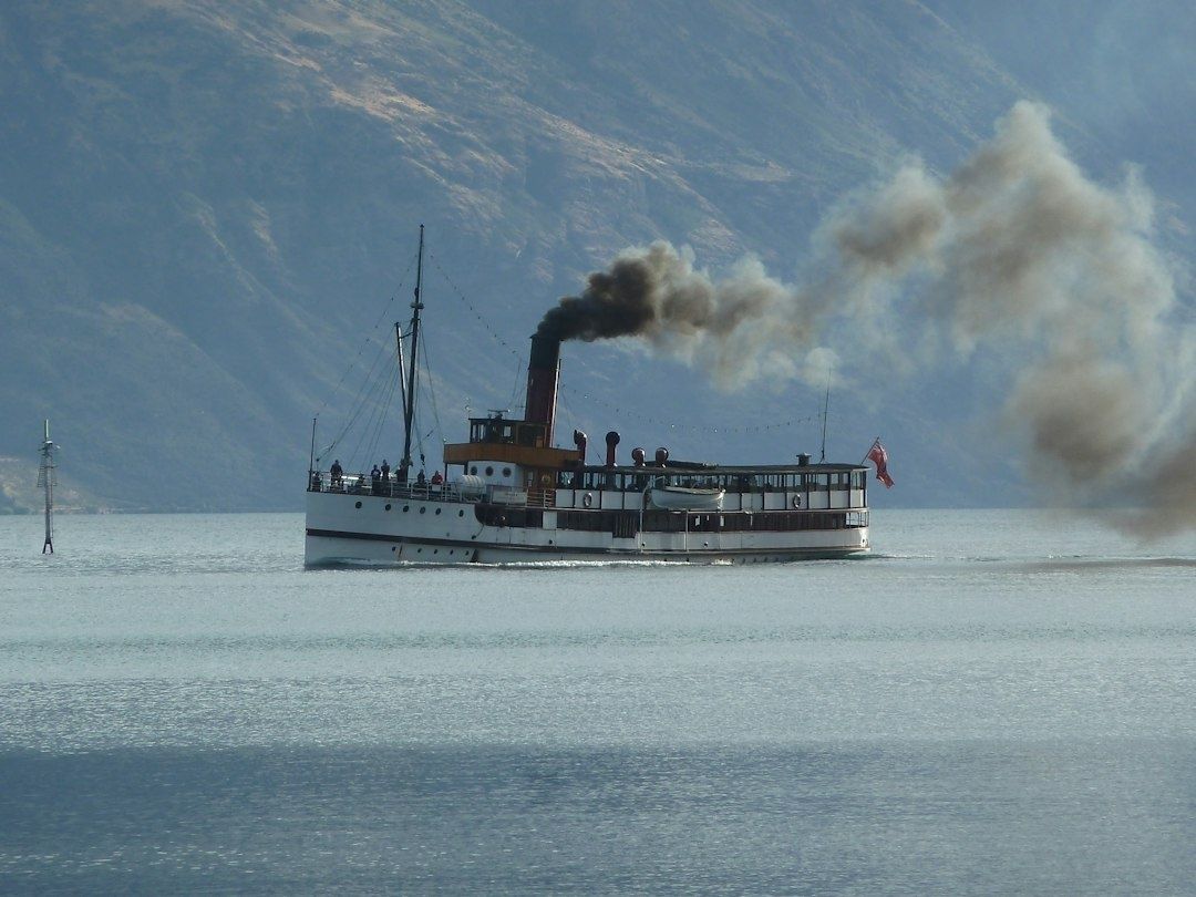 Vintage steam ferry crossing calm water beneath smoky mountains